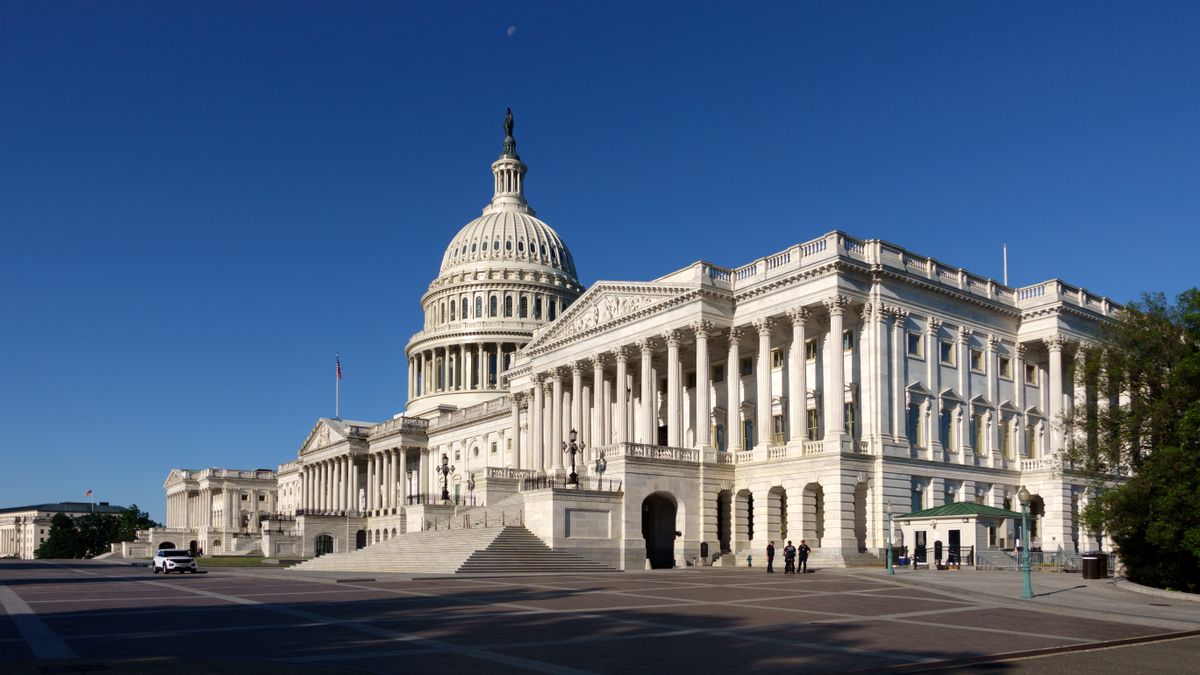 An angular view of the U.S. Capitol building against a clear blue sky.