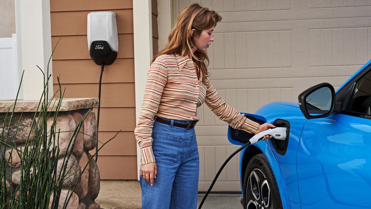 A person plugs in an electric Ford Mustang Mach e for charging.