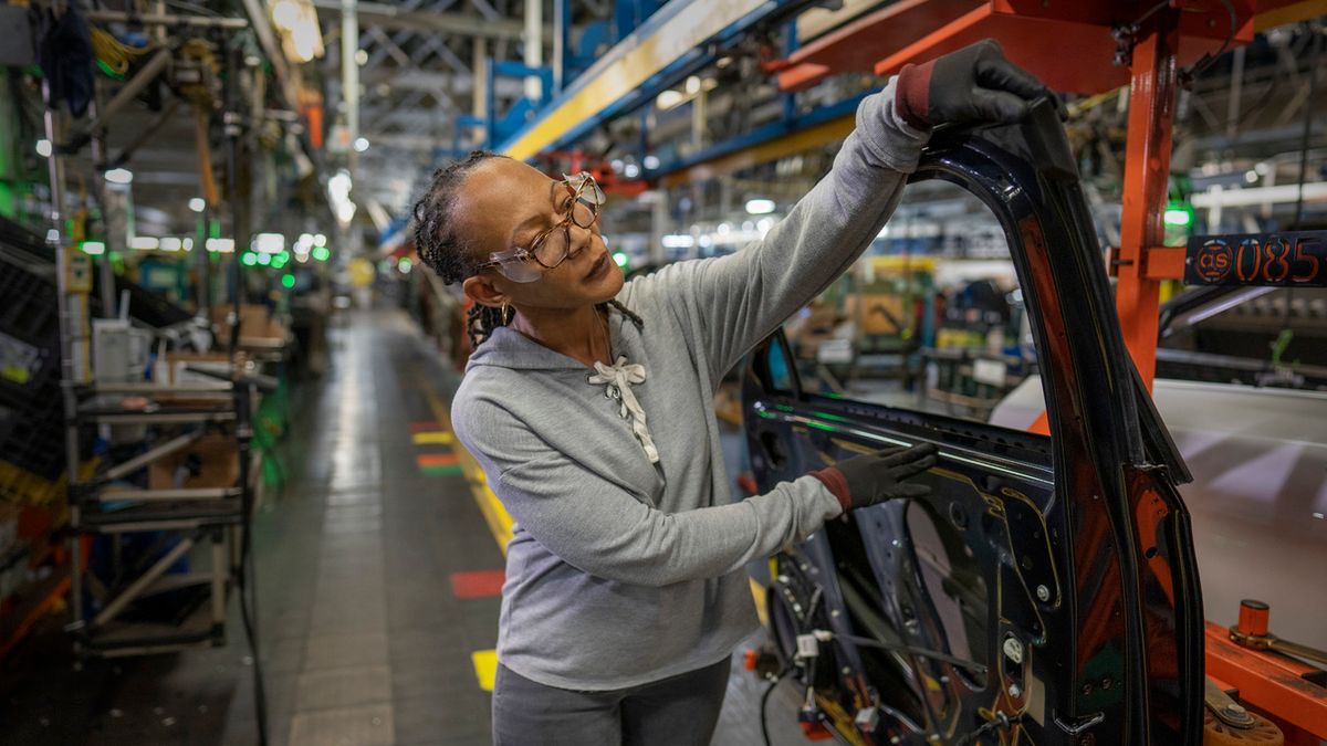 Autoworker installing a car door.