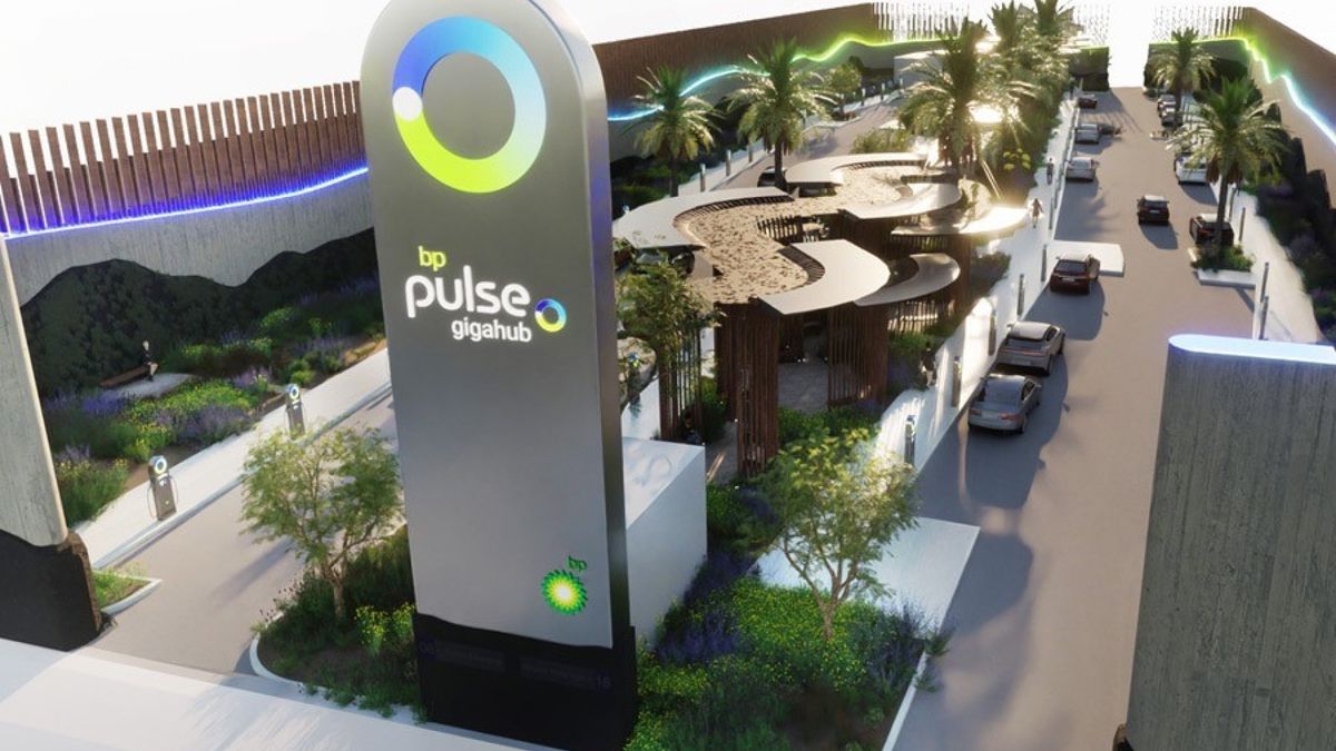 Illustration looking down at a large electric vehicle charging station with several cars parking alongside chargers and a large sign reading "bp pulse gigahub."