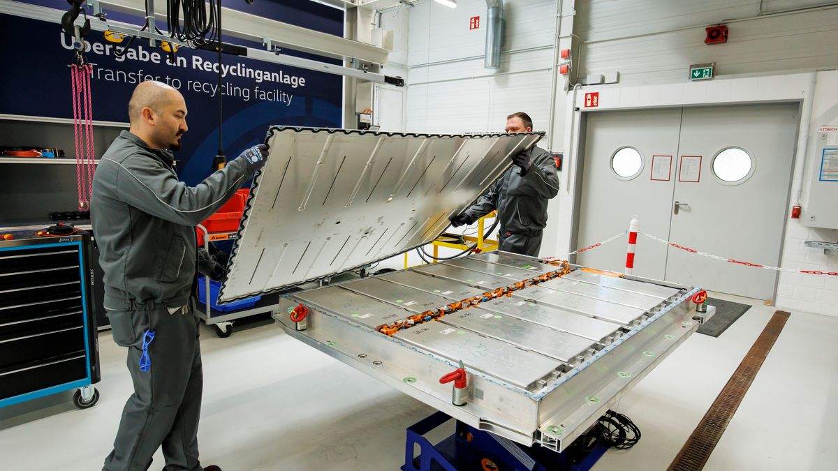 Two Volkswagen employees demonstrate the disassembling of an electric car battery.