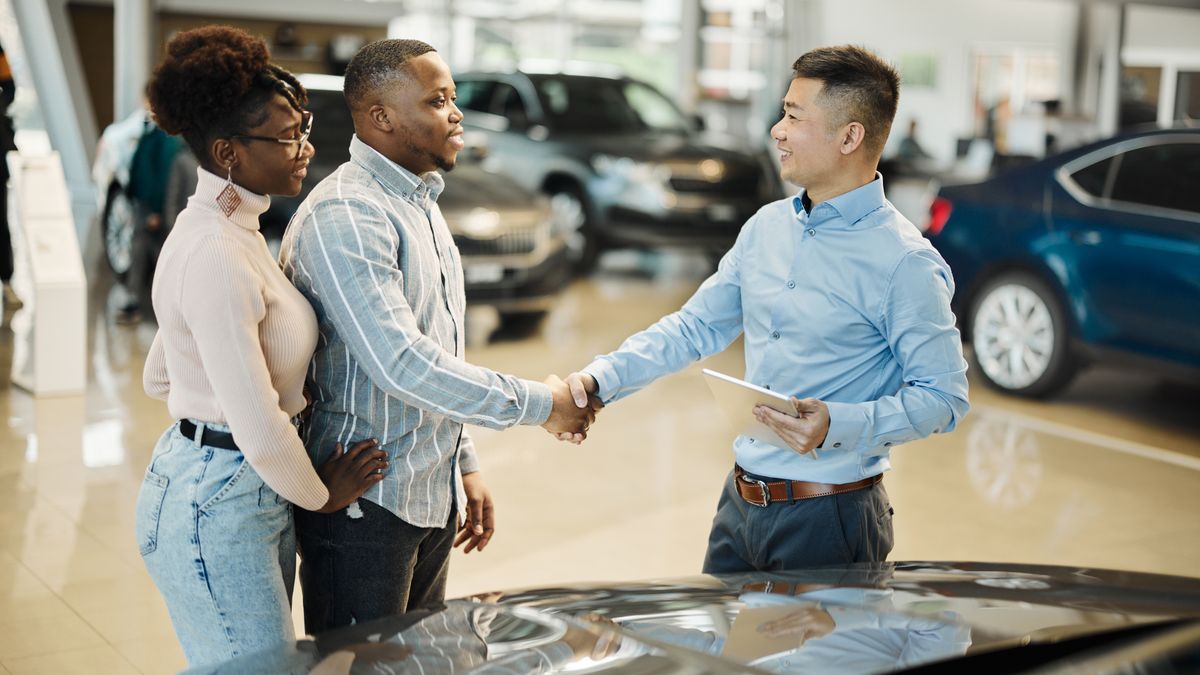 A car salesperson shaking hands with a customer.