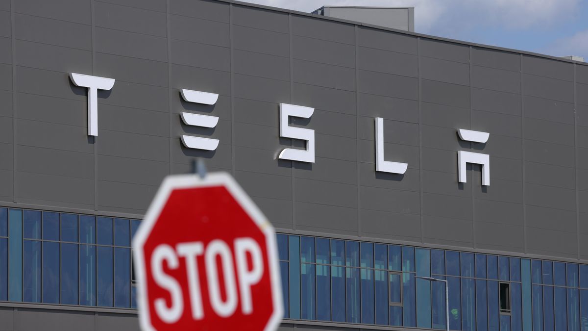 A stop sign in front of a Tesla factory.