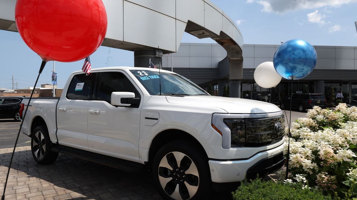 A white 2023 Ford F-150 Lightning EV is offered for sale at a Ford dealer in Illinois.