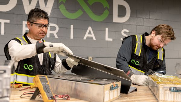 Two employees at Redwood Materials disassemble batteries for recycling.